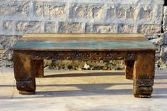 an old wooden bench sitting in front of a stone wall with carvings on the top