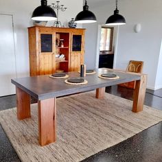 a dining room table and chairs in front of a wooden cabinet with black lights hanging from the ceiling