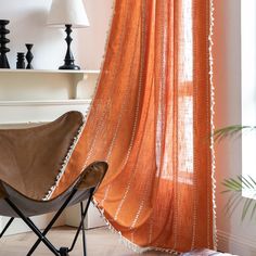 an orange curtain hanging over a chair next to a window