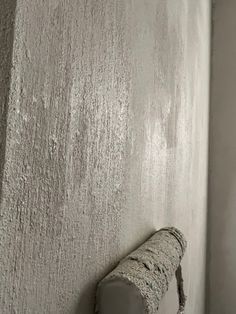 a cement wall with a concrete pipe sticking out of it's corner and the paint peeling off