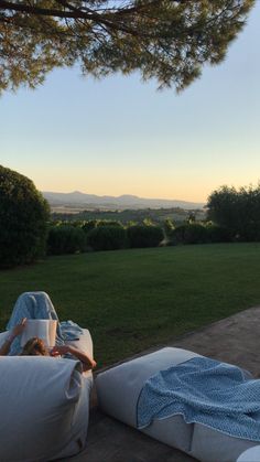 a woman laying on top of a white bean bag chair next to a lush green field