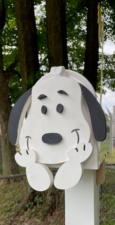 a white and black dog mailbox with trees in the background