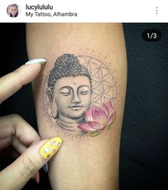 a woman's arm with a buddha tattoo on it and a pink flower in front of her