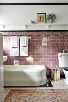 a white toilet sitting next to a bath tub in a bathroom on top of a rug