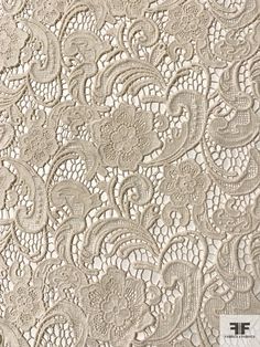 an image of a white lace fabric with flowers and leaves on the side, as well as