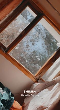 an open window in the corner of a room with snow on the ground and trees outside