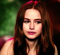 a close up of a person with long hair and red lipstick on her face, looking at the camera