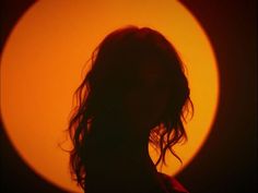 the silhouette of a woman's head in front of an orange and yellow circle