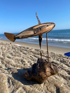 a piece of driftwood on the beach with a knife stuck in it