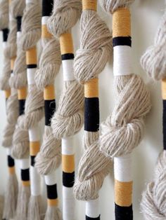 several skeins of yarn hanging on a wall with black and white striped ropes