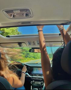 two women driving in the back seat of a car with their hands on the dashboard