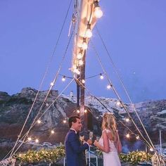 a man and woman standing next to each other in front of a boat at night