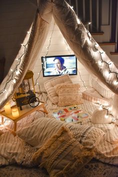 a bed that has some lights on it and a tv in the corner behind it