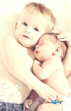 a woman holding a baby in her arms while laying on top of the floor next to him