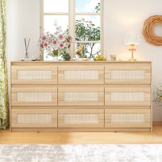 an empty room with a dresser and flowers on the window sill in front of it