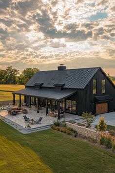 a large black barn with a covered patio and fire pit in the middle of it