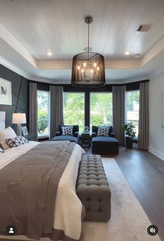 a large bed sitting in a bedroom under a chandelier next to a window