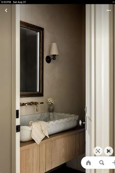 a bathroom sink sitting under a mirror next to a light on top of a wooden cabinet