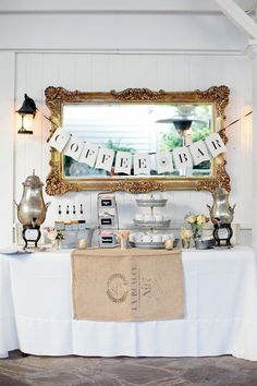 a table with a sign that says happy birthday hanging from it's side and some teapots on top