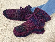 a pair of crocheted slippers sitting on top of a white carpet next to someone's legs