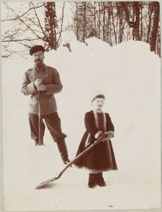 an old black and white photo of two people in the snow, one holding ski poles