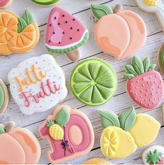 some decorated cookies are sitting on a white table and there is a sign that says little fruitie