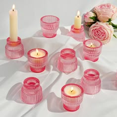 pink glass candles are arranged on a white cloth