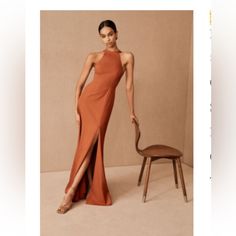 a woman in an orange dress standing next to a chair