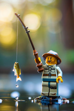 a lego man holding a fishing rod and a fish on the water with it's hook