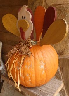 a wooden turkey sitting on top of a pumpkin