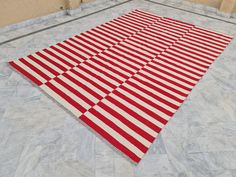 a red and white striped rug sitting on top of a tile floor next to a wall