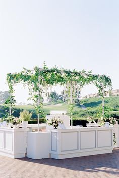 an outdoor wedding setup with white furniture and greenery