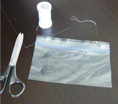 a pair of scissors sitting on top of a wooden floor next to a plastic bag