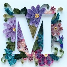 the letter m is made out of paper and decorated with colorful flowers, leaves and butterflies