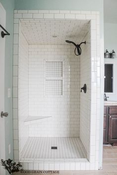 a white tiled shower in a bathroom next to a sink