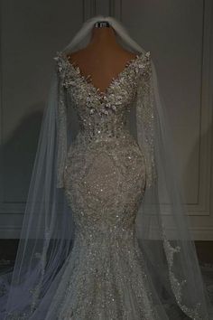 the back of a wedding dress with long sleeves and beading on it, in front of