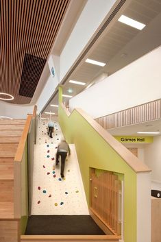 a man climbing up the stairs in a building with lots of wood and white walls