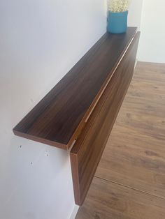 a vase with flowers on top of a wooden shelf