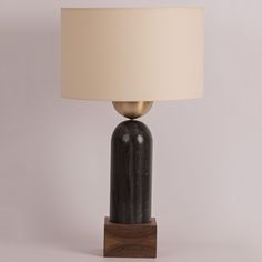 a black table lamp with a white shade on it's base and a wooden base