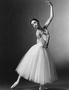 a black and white photo of a woman in a tutu skirt with her arm raised