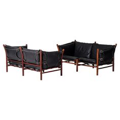 a set of three black leather and wood sofas with metal rings on the armrests