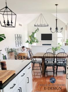 an open concept kitchen and dining room with white cabinets, wood flooring and black accents