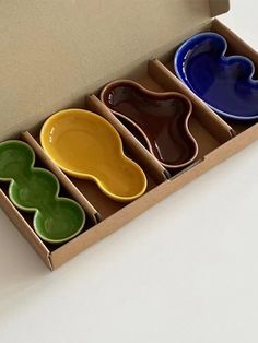 four different colored bowls in a cardboard box