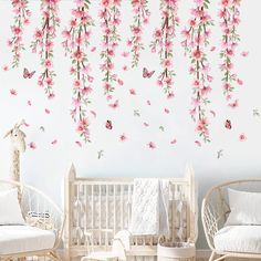 a baby's room with pink flowers on the wall and white cribs