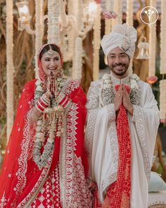 two people standing next to each other wearing red and white wedding outfits with flowers on them