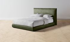 a bed that is sitting on top of a hard wood floor with white sheets and pillows