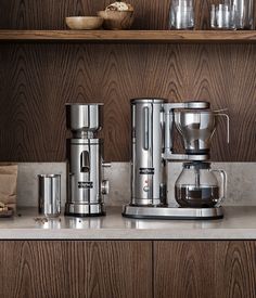 a coffee maker sitting on top of a counter next to cups and bowls filled with liquid