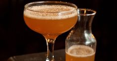 a close up of a drink in a glass near a bottle