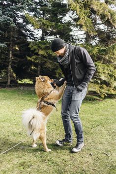 a man is playing with his dog in the park