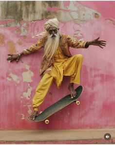 a man with long white hair and beard on a skateboard in front of a pink wall